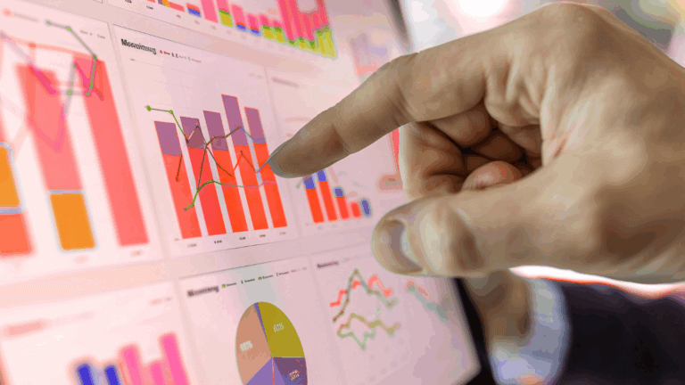 Hand pointing at bar charts and graphs on a screen
