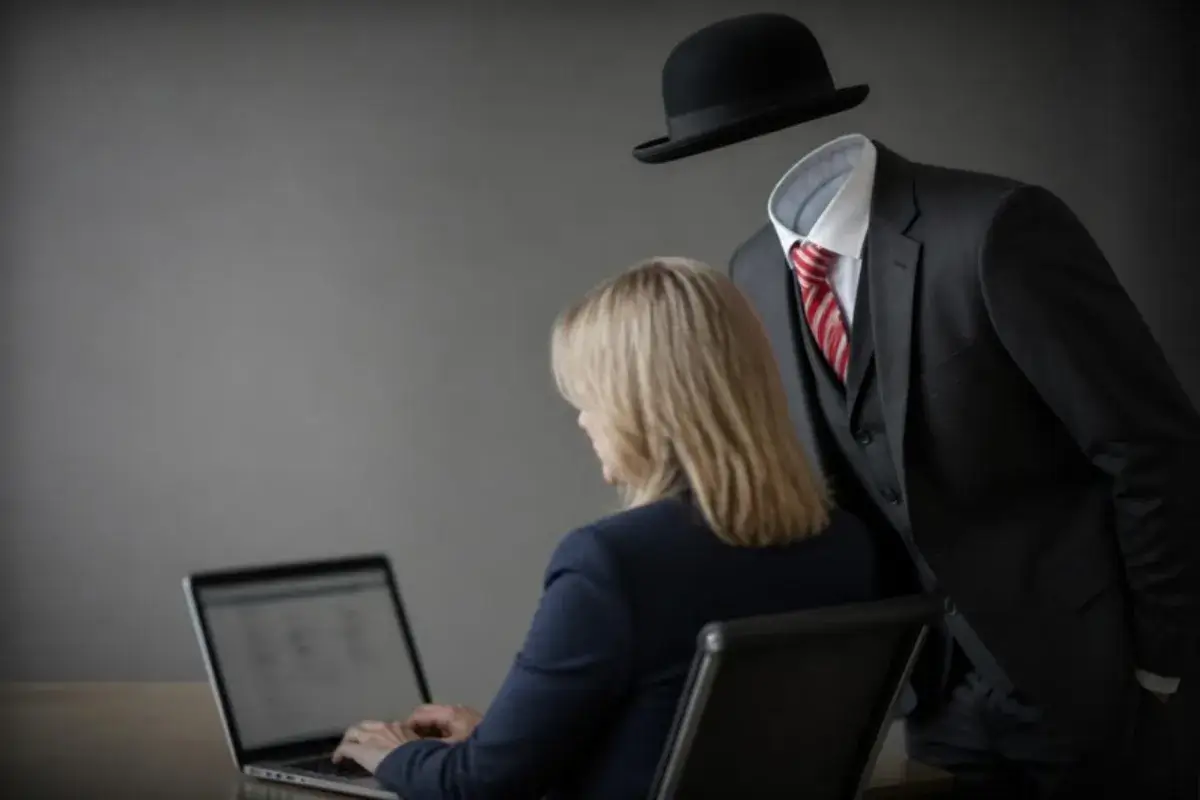 Illustration: an invisible figure in a suit and bowler hat watches over the shoulder of a woman asking an AI assistant for a recommendation.